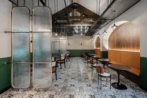 Interior design featuring industrial-style cafe with glass partitions, metallic elements, and patterned floor tiles.