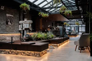 Industrial-themed restaurant bar featuring concrete flooring, metal accents, and glass plants.