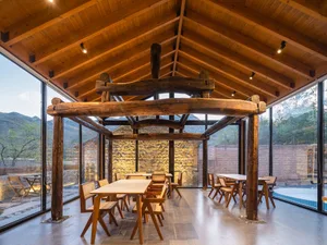 An industrial-style restaurant with wooden tables and chairs, featuring natural stone walls and a rustic ambiance.