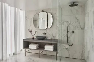 A minimalist bathroom with marble features and a glass shower enclosure.
