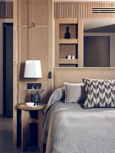 A minimalist bedroom with renewable materials and a light-colored wood bed frame and nightstand.