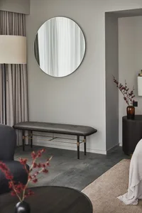 A minimalist living space featuring a round mirror, upholstered bench, and elegant decorative elements.