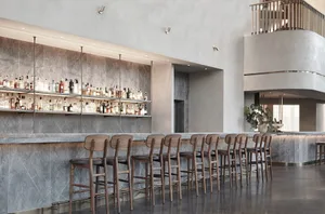 Modern minimalist bar with marble countertop and wooden barstools.