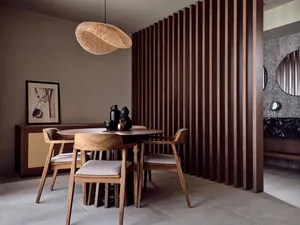A modern dining room featuring wooden furniture and a woven light fixture.
