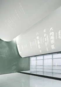 Modern installation art featuring textured paper on a curved wall and white room with glass partition.