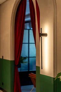 Modern architecture with white and green colors, red curtains, and a wall-mounted light fixture.