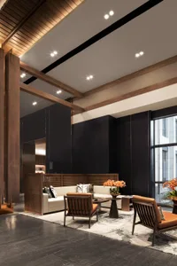 A modern lobby with wooden beams, white sofas, and orange armchairs
