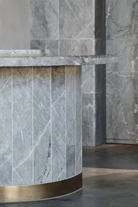 A modern marble reception counter with a brass base in a contemporary interior design setting.