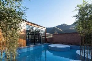 Modern minimalist residential patio featuring sleek glass walls overlooking mountains.