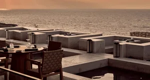 A modern patio with concrete furniture and a view of the ocean.