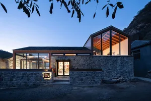 A modern residential building with stone exterior and large glass windows.