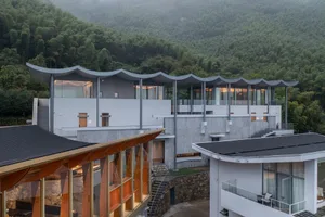 Modern residential building featuring a wave-like roof and extensive use of glass.