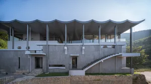 A modern residential building with a concrete exterior and large glass panels.