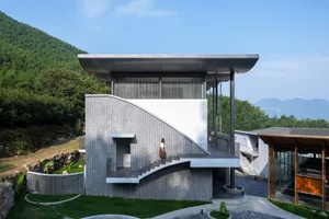 Modern residential exterior with concrete walls, matte black metal accents, terraces, and balconies overlooking greenery and 