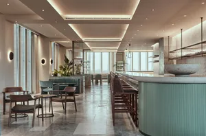 A modern restaurant bar with concrete and glass elements and green plants.