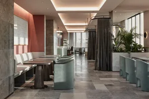 Modern restaurant interior with concrete flooring, white seating, and green plants.