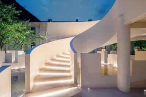 A modern sculpture space with illuminated elements and a curved staircase.