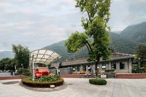 一棟磚牆與混凝土外牆的建築，坐落於果園內，周圍環繞綠意與樹木的戶外景觀