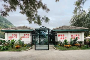 傳統中式建築外觀，入口為玻璃門，搭配綠色植物與牆面紅色標語。