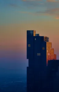 A tall building with glass walls reflecting the sunset.