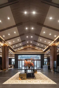 A spacious hotel lobby with a large wooden vase centerpiece and a high, vaulted wooden ceiling.