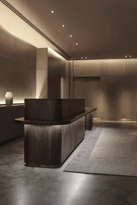 A modern interior reception area featuring a wooden desk and lighting.