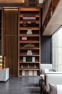 A modern lobby featuring a tall wooden bookshelf with various decorative items and books.