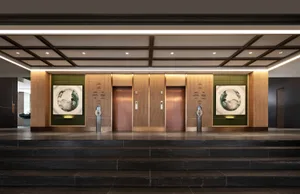 Modern lobby with green wood panels, abstract art, and metal elevators.