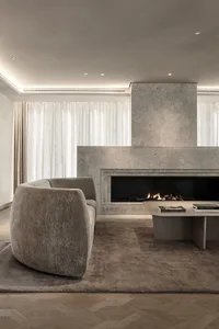 Modern minimalist living room featuring a concrete fireplace and neutral-colored furniture.