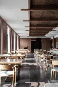 Modern restaurant interior with wooden tables, chairs, and marble accents.