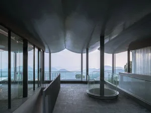 Modern interior with glass balcony overlooking mountains and hills.