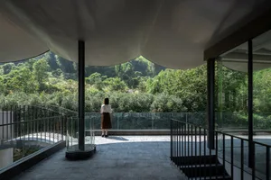 A modern interior space with a glass verandah overlooking greenery.
