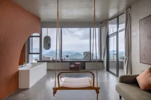 Modern living room featuring a wood swing hanging from the ceiling, a large window with a view of the mountains, and a sofa w