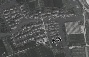 Aerial view of a village with houses arranged around a network of canals and fields.