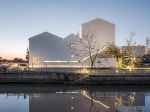 Modern architectural building with a concrete facade reflected in the water at dusk