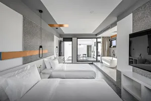Modern, spacious hotel suite featuring minimalist design with concrete walls and floors.