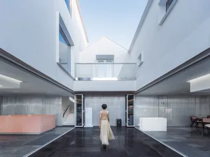 A modern interior space with glass walls, concrete floors, and metallic accents.