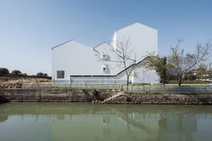 A modern white building with a concrete exterior located by a river.
