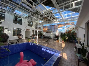 A modern, spacious lounge area featuring concrete flooring and a poolside seating area with a pink flamingo float.
