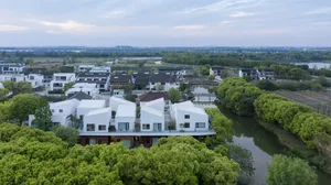 Aerial view of modern residential architecture featuring white brick and concrete materials.