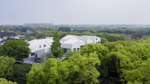 A modern white house surrounded by lush green trees.
