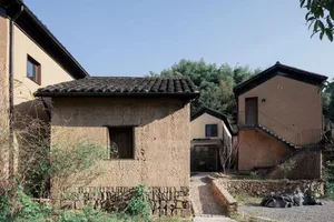 Traditional clay residential building with a tiled roof and stone foundation.