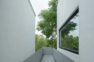 Modern exterior wall made of concrete with trees in the background.