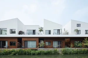Modern white and brown concrete housing with large windows and balconies.