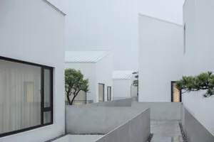 A modern residential exterior with white walls and concrete floors.