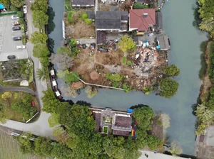 Aerial view of residential buildings along a waterfront, with trees and a canal.
