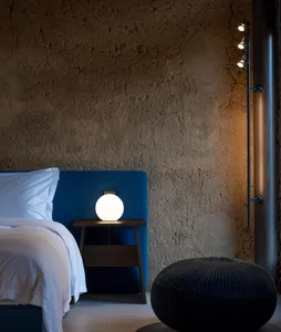 A modern bedroom featuring a concrete wall and blue upholstered bed frame.