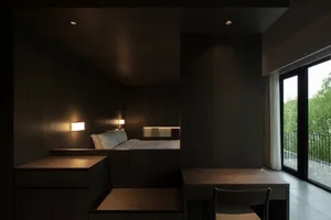 A modern, minimalist bedroom with dark wood accents and neutral color tones.