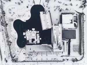 Aerial view of a modern building covered in snow with a minimalist architectural design.
