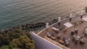 A modern terraced lounge overlooking the sea with wooden flooring and furniture.